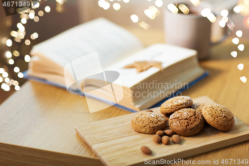 Image of oat cookies, almonds and book on table at home