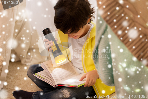 Image of happy boy reading book in kids tent at home