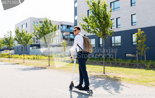 Image of businessman with backpack riding electric scooter