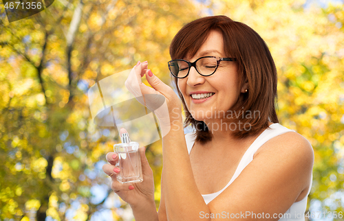 Image of senior woman smelling perfume from her wrist