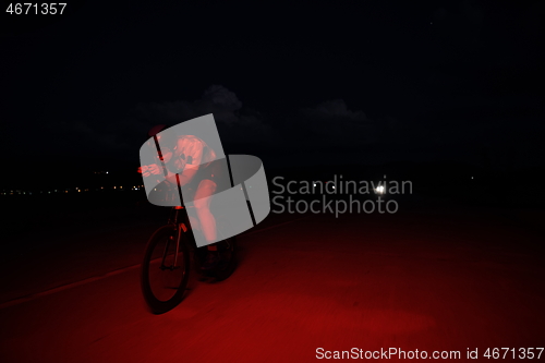 Image of triathlon athlete riding bike fast at night