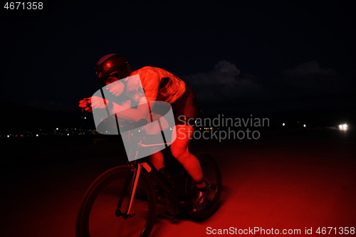 Image of triathlon athlete riding bike fast at night