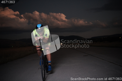 Image of triathlon athlete riding bike fast at night