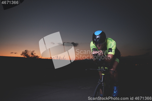 Image of triathlon athlete riding bike fast at night