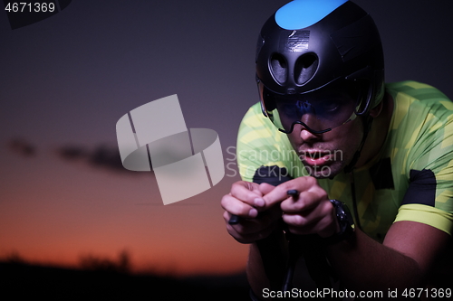 Image of triathlon athlete riding bike fast at night