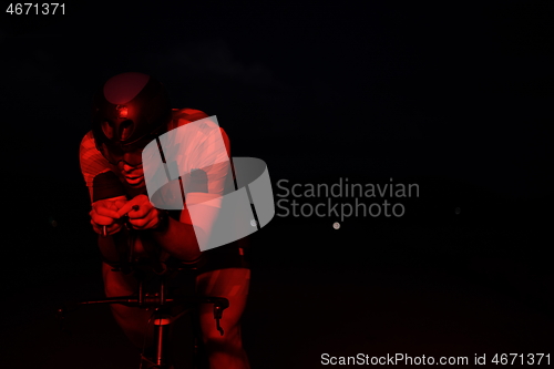 Image of triathlon athlete riding bike fast at night