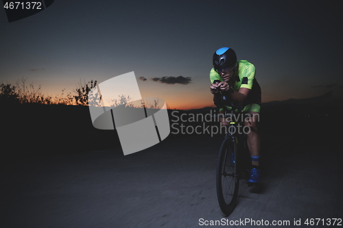 Image of triathlon athlete riding bike fast at night