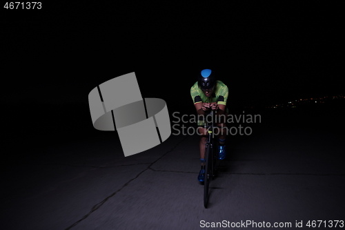 Image of triathlon athlete riding bike fast at night