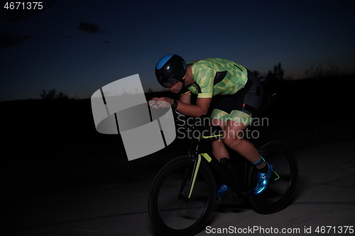 Image of triathlon athlete riding bike fast at night