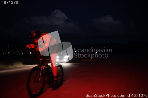 Image of triathlon athlete riding bike fast at night