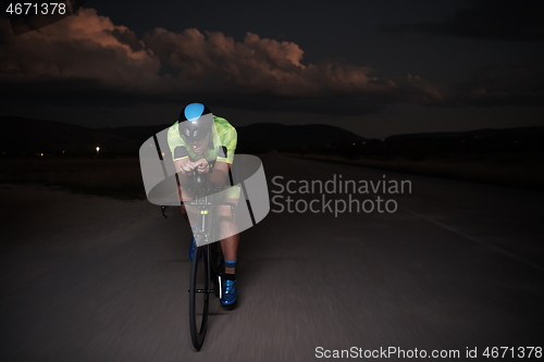 Image of triathlon athlete riding bike fast at night