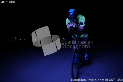 Image of triathlon athlete riding bike fast at night