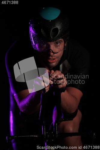 Image of triathlon athlete riding bike fast at night