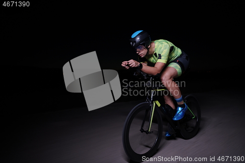 Image of triathlon athlete riding bike fast at night