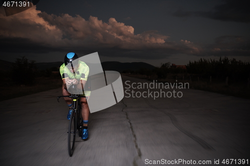 Image of triathlon athlete riding bike fast at night