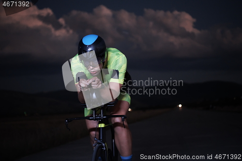 Image of triathlon athlete riding bike fast at night