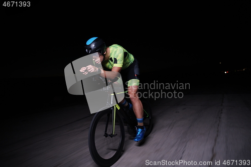 Image of triathlon athlete riding bike fast at night