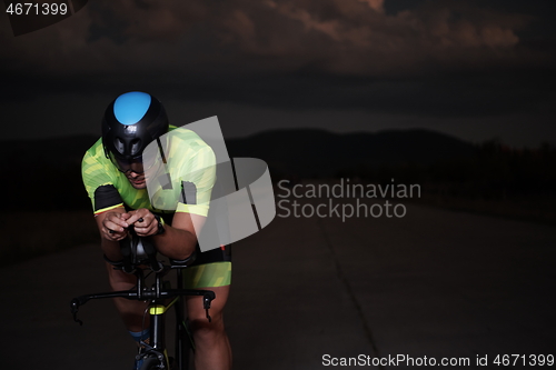 Image of triathlon athlete riding bike fast at night
