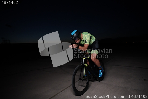 Image of triathlon athlete riding bike fast at night