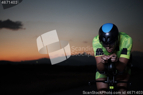 Image of triathlon athlete riding bike fast at night