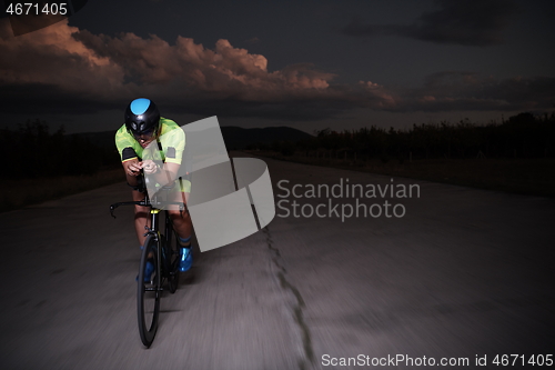 Image of triathlon athlete riding bike fast at night