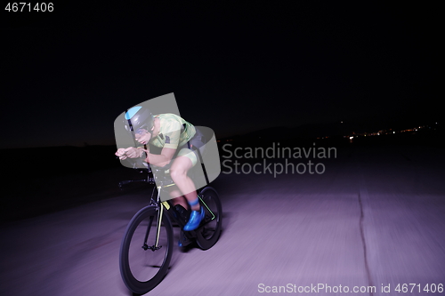 Image of triathlon athlete riding bike fast at night