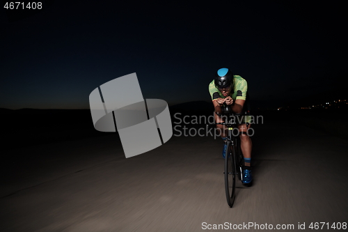 Image of triathlon athlete riding bike fast at night