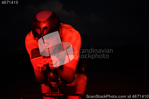 Image of triathlon athlete riding bike fast at night