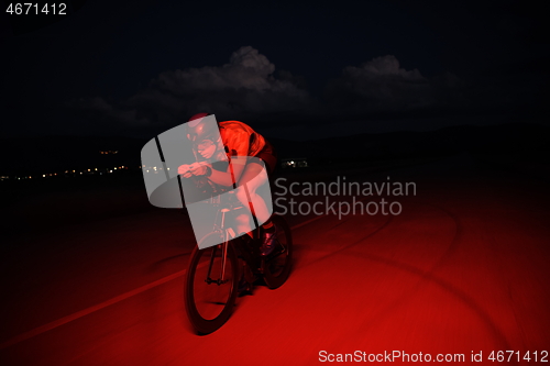 Image of triathlon athlete riding bike fast at night