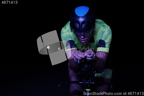 Image of triathlon athlete riding bike fast at night