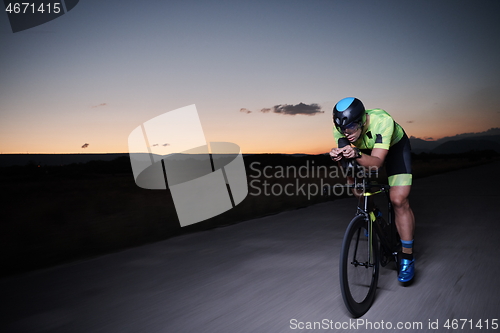 Image of triathlon athlete riding bike fast at night