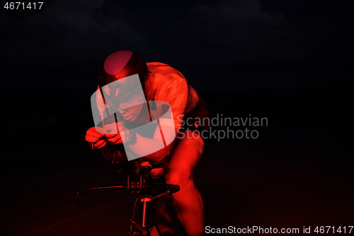 Image of triathlon athlete riding bike fast at night