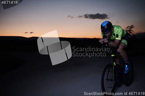 Image of triathlon athlete riding bike fast at night