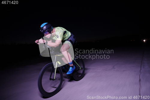 Image of triathlon athlete riding bike fast at night