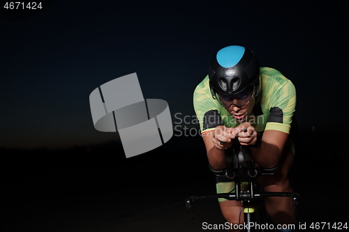 Image of triathlon athlete riding bike fast at night