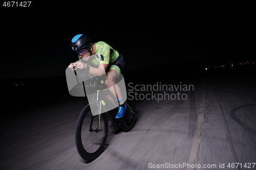 Image of triathlon athlete riding bike fast at night