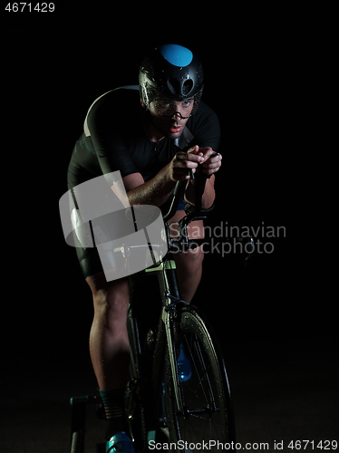 Image of triathlon athlete riding bike fast at night