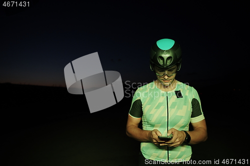 Image of athlete cyclist having a break using smart phone