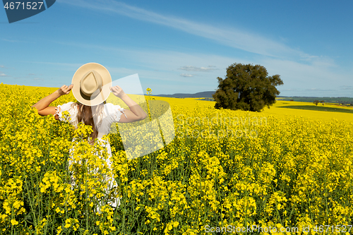Image of Woman in white dress in field of golden canola