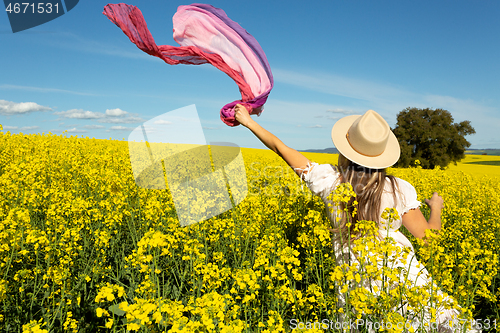 Image of Woman in whte dress and floating scarf in canola field