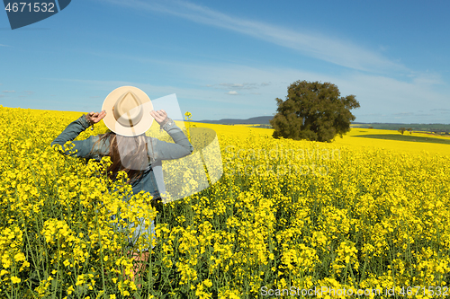 Image of Female in denim jacket and shorts  in a field of flowering canol