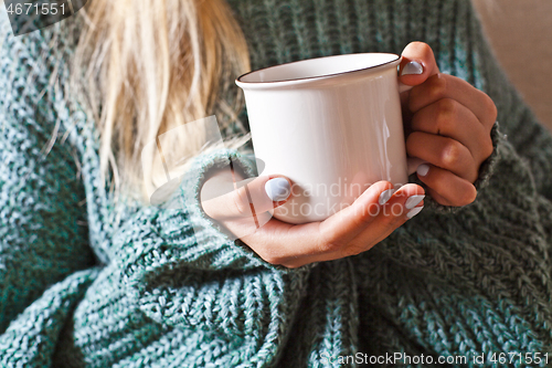 Image of Female hands holding mug of hot tea with lemon in morning.