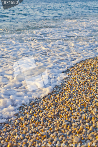 Image of Pebble stones by the sea. Waves of blue Tyrrhenian sea.