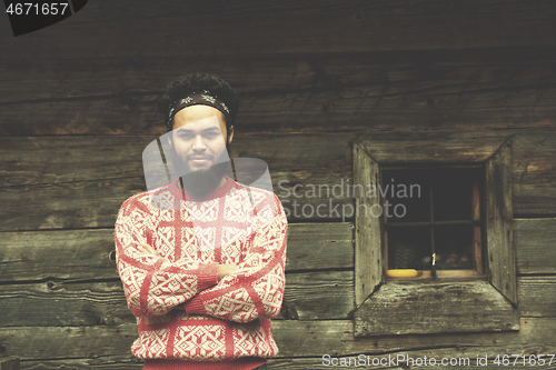 Image of portrait of young hipster in front of wooden house