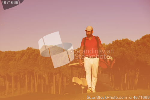 Image of golfer  walking and carrying golf  bag