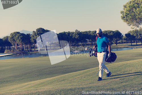 Image of golf player walking and carrying bag