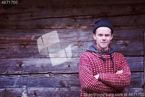 Image of young hipster in front of wooden house
