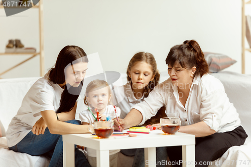 Image of Little girls, attractive young mother and charming grandmother are sitting at home