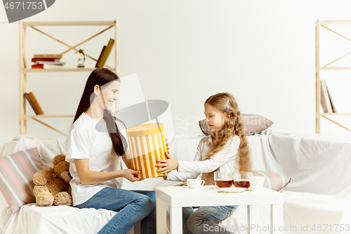 Image of Little girl, attractive young mother are sitting at home