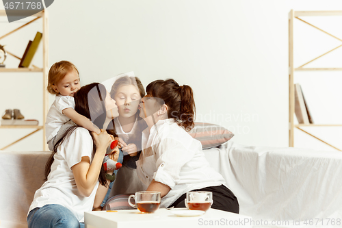 Image of Little girls, attractive young mother and charming grandmother are sitting at home